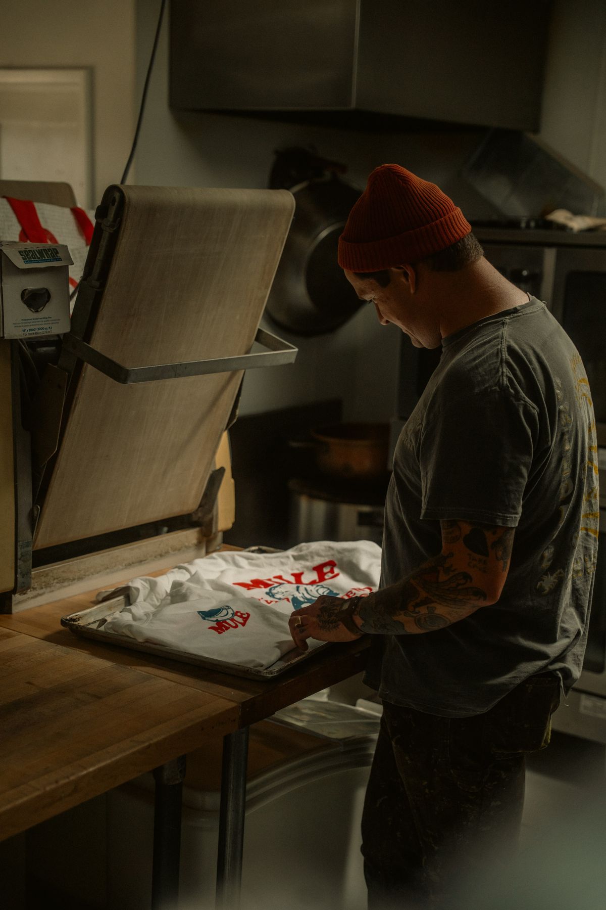 Impresor colocando playeras recién estampadas en la plancha del taller